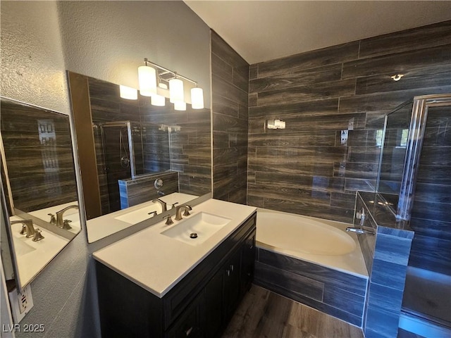 full bath with vanity, a shower stall, a bath, and wood finished floors