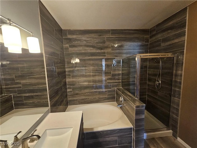 bathroom with a garden tub, wood finished floors, a stall shower, and vanity