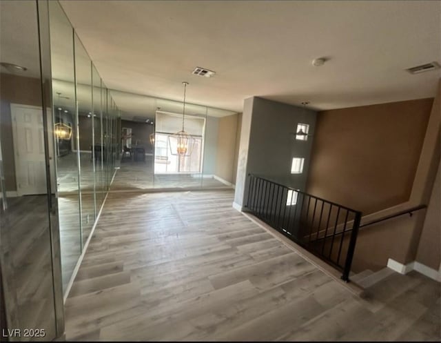 interior space with baseboards, a notable chandelier, visible vents, and wood finished floors