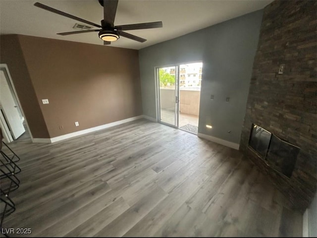 unfurnished living room featuring wood finished floors, visible vents, a fireplace, ceiling fan, and baseboards
