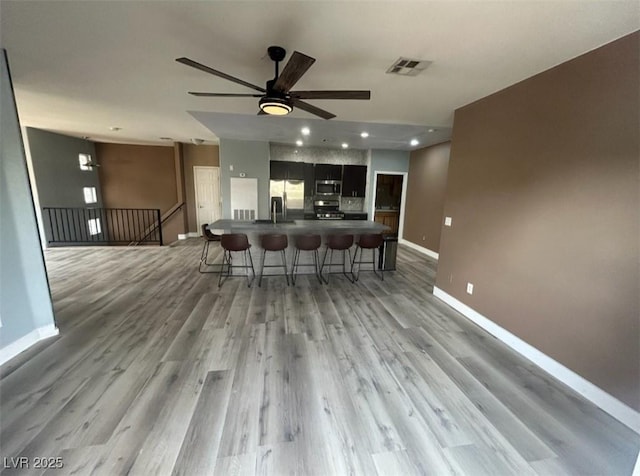 interior space with a breakfast bar area, baseboards, visible vents, dark countertops, and appliances with stainless steel finishes