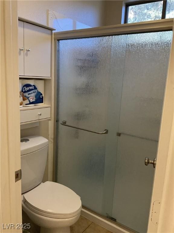 bathroom with an enclosed shower, tile patterned floors, and toilet