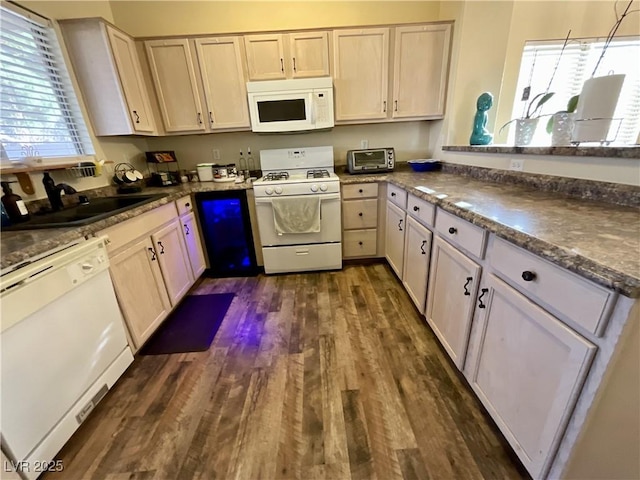 kitchen with sink, dark stone counters, kitchen peninsula, dark wood-type flooring, and white appliances