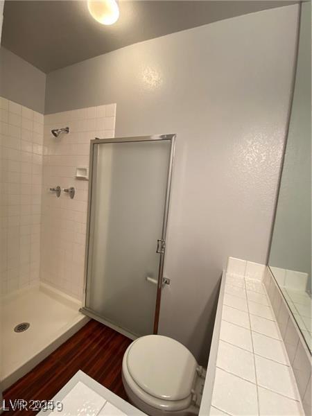 bathroom with walk in shower, toilet, and hardwood / wood-style flooring