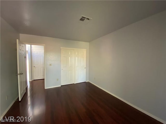 unfurnished bedroom with dark hardwood / wood-style floors and a closet