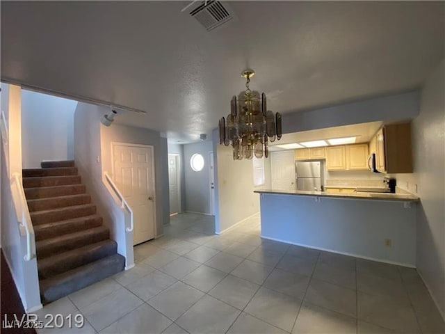 interior space with an inviting chandelier, light tile patterned floors, stainless steel appliances, and kitchen peninsula