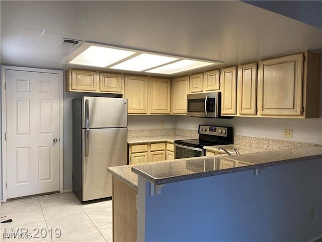 kitchen with light tile patterned floors, a kitchen breakfast bar, stainless steel appliances, and kitchen peninsula