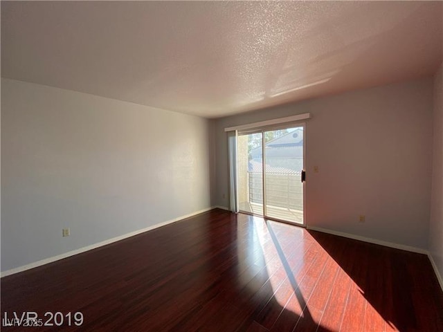 empty room featuring dark hardwood / wood-style flooring and a textured ceiling