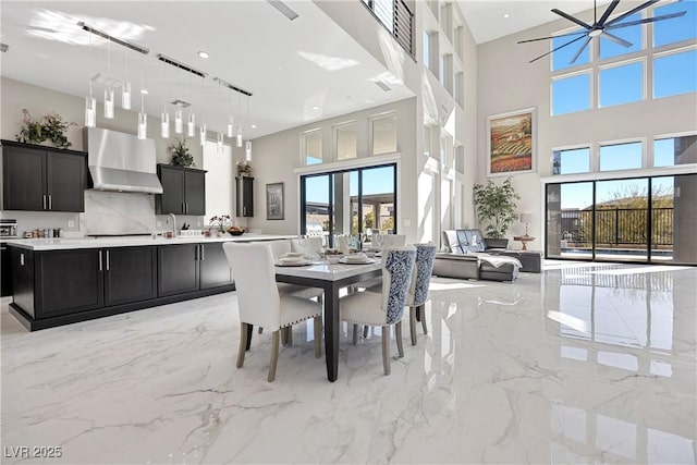 dining area with ceiling fan, sink, and a high ceiling