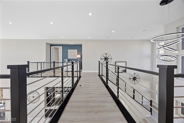 corridor with light hardwood / wood-style flooring and a notable chandelier