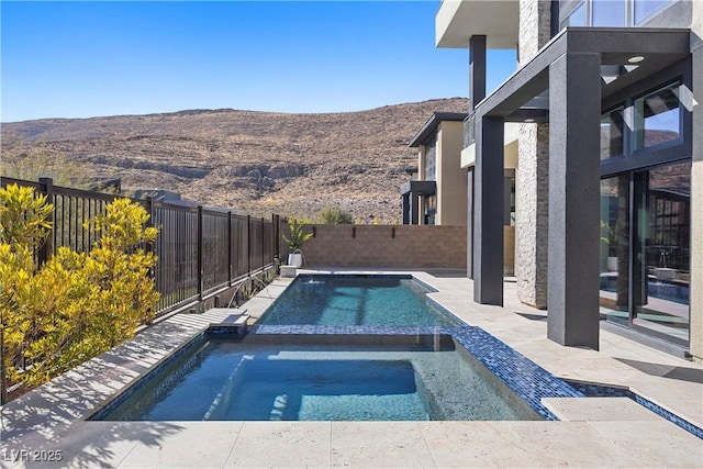 view of swimming pool with a mountain view and an in ground hot tub