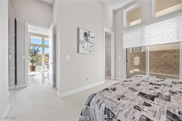 bedroom with ensuite bath, light colored carpet, and a high ceiling