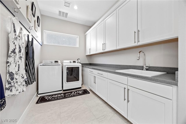 clothes washing area featuring separate washer and dryer, sink, and cabinets