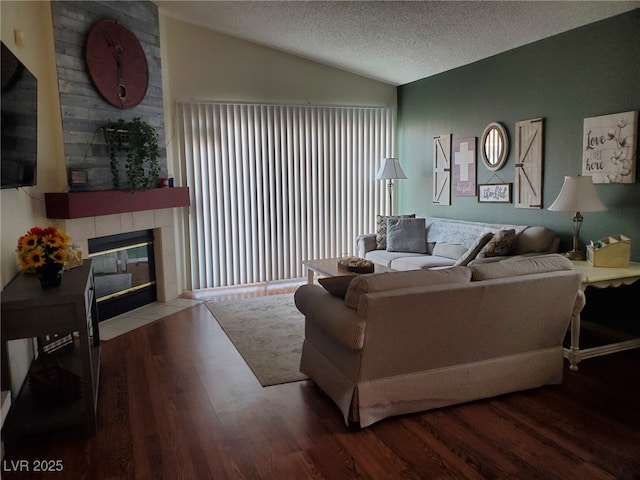 living room with hardwood / wood-style floors, vaulted ceiling, a large fireplace, and a textured ceiling