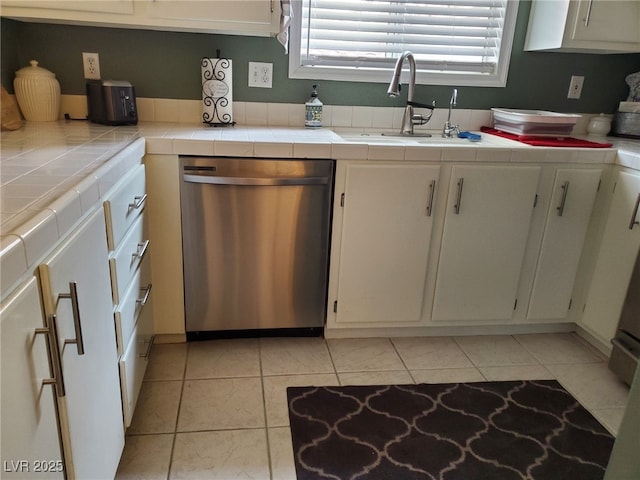 kitchen with white cabinetry, stainless steel dishwasher, tile counters, and sink