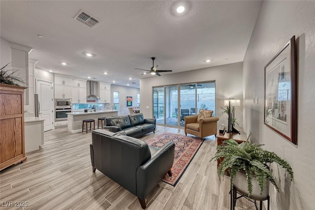 living room with ceiling fan, sink, and light hardwood / wood-style flooring