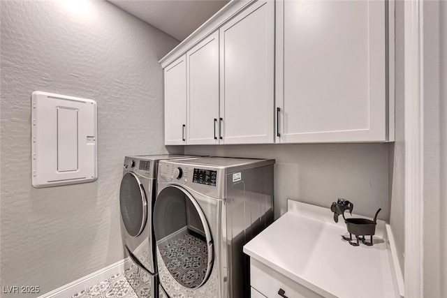 clothes washing area with cabinets and washing machine and clothes dryer