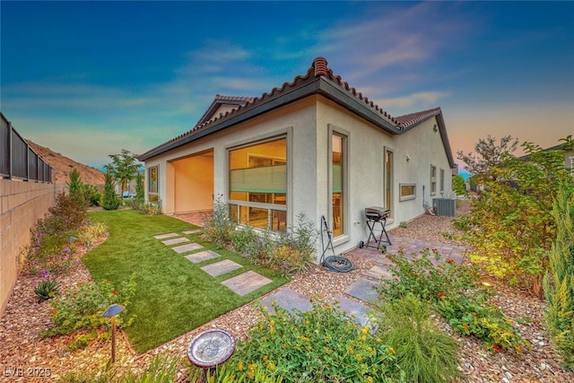 property exterior at dusk featuring central AC and a lawn