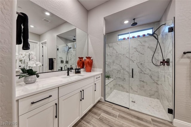 bathroom featuring a shower with door and vanity