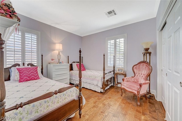 bedroom featuring ornamental molding, a closet, and light hardwood / wood-style flooring