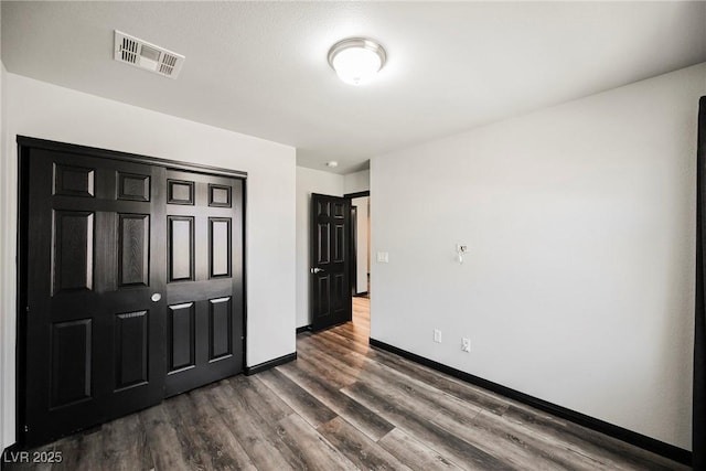 bedroom with dark hardwood / wood-style flooring and a closet