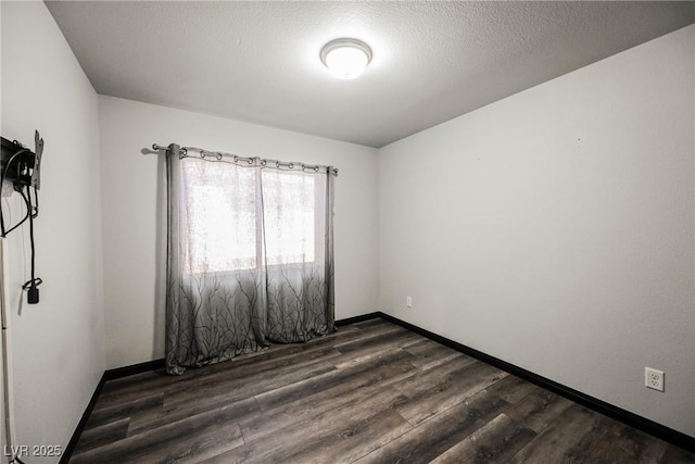 spare room with dark wood-type flooring and a textured ceiling