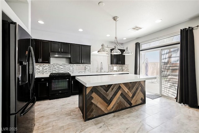 kitchen featuring pendant lighting, sink, backsplash, a center island, and black appliances