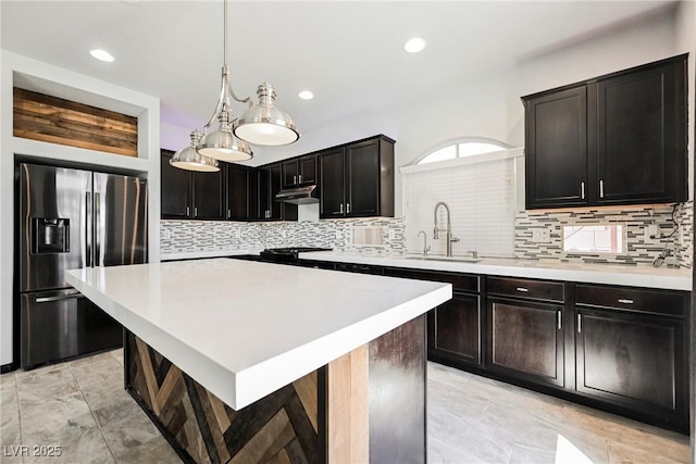 kitchen with sink, stainless steel fridge, backsplash, a center island, and decorative light fixtures