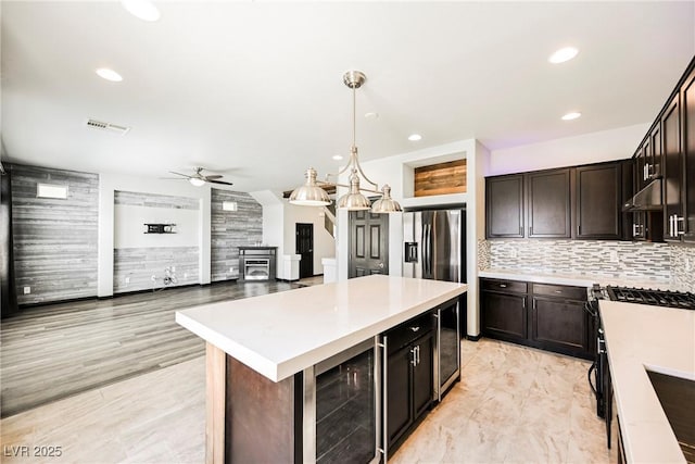 kitchen featuring tasteful backsplash, wine cooler, hanging light fixtures, stainless steel appliances, and dark brown cabinets