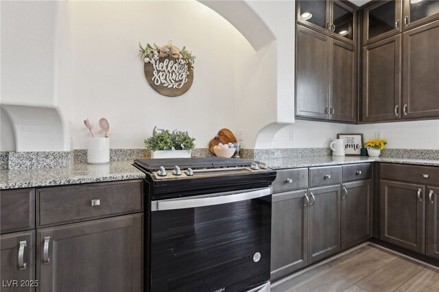 kitchen with light stone counters, dark brown cabinetry, light hardwood / wood-style floors, and range with gas cooktop