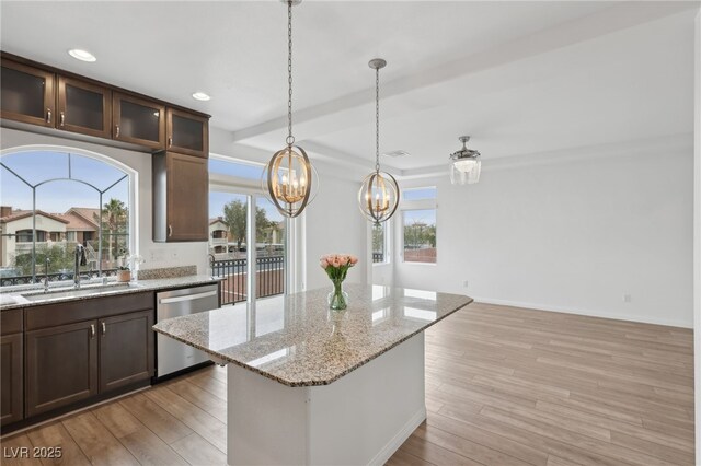 kitchen featuring sink, light hardwood / wood-style flooring, dishwasher, light stone counters, and a kitchen island