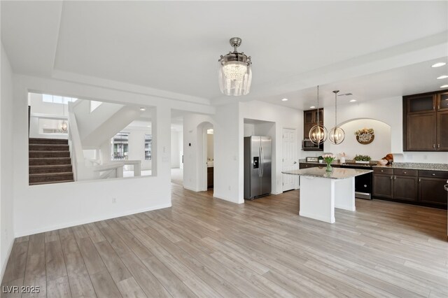 kitchen featuring an inviting chandelier, dark brown cabinets, appliances with stainless steel finishes, a kitchen island, and light hardwood / wood-style floors