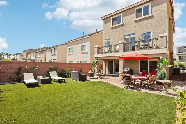 rear view of house with a yard, a patio, and a balcony