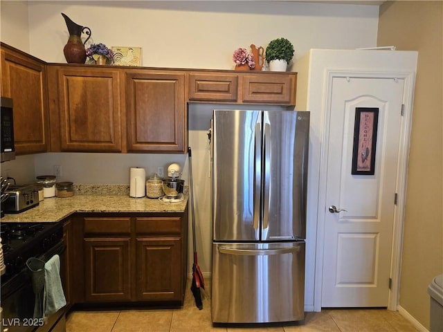 8985 S Durango Dr Unit 2062, Las Vegas, NV 89113 - kitchen featuring gas stove, light stone counters, light tile patterned floors, and freestanding refrigerator