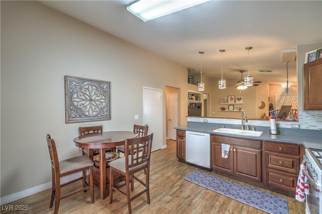 kitchen with light hardwood / wood-style floors, dishwasher, sink, and hanging light fixtures