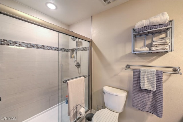 bathroom featuring a shower with shower door and toilet