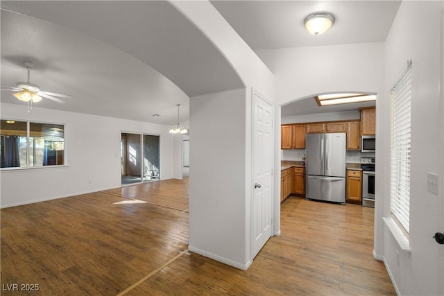 kitchen with hanging light fixtures, ceiling fan with notable chandelier, light hardwood / wood-style flooring, and appliances with stainless steel finishes