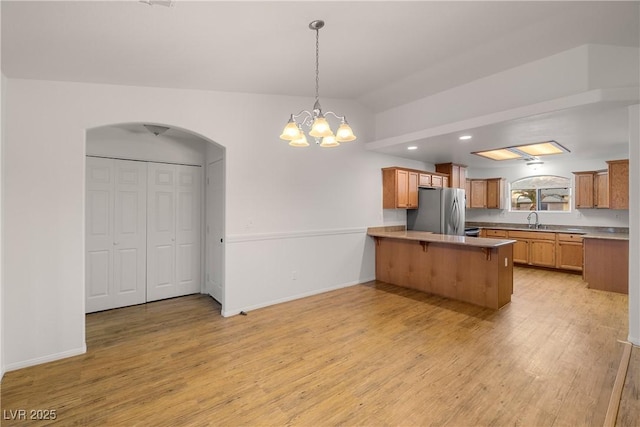 kitchen with vaulted ceiling, a breakfast bar, stainless steel refrigerator, sink, and kitchen peninsula