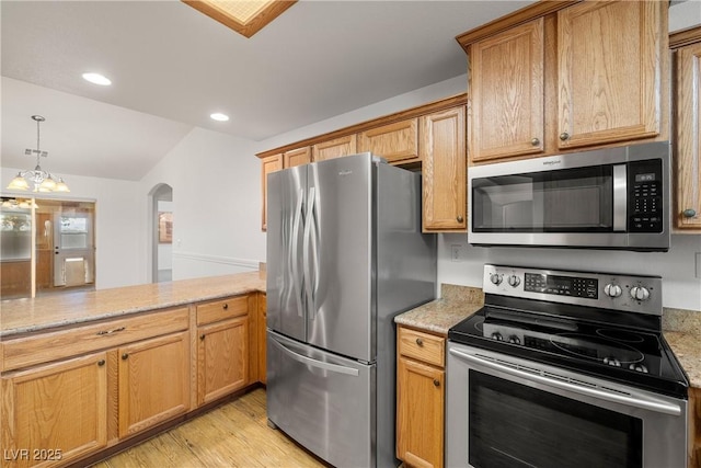 kitchen with pendant lighting, a notable chandelier, stainless steel appliances, light stone countertops, and light wood-type flooring