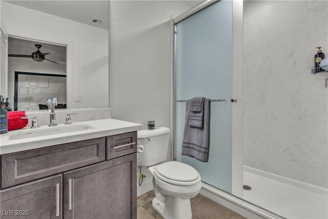 bathroom featuring vanity, toilet, ceiling fan, and a shower with shower door