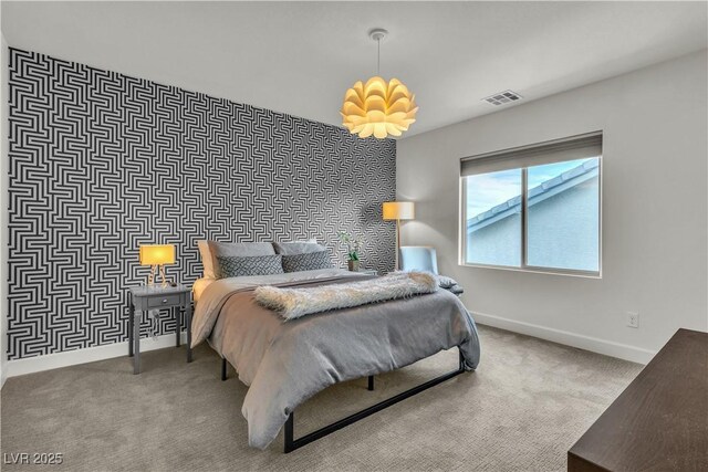 carpeted bedroom featuring an accent wall, visible vents, and baseboards