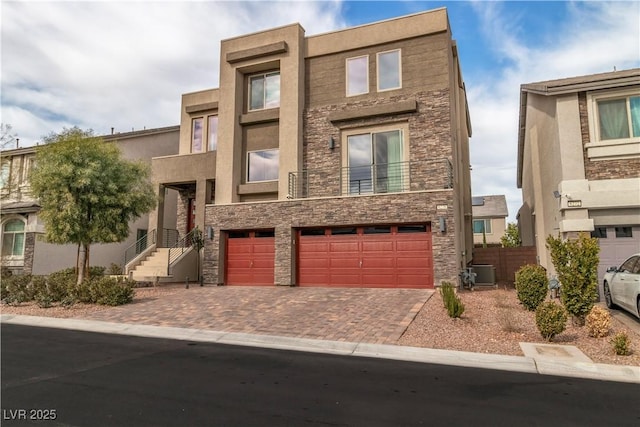 view of front of property featuring a garage, stone siding, and decorative driveway