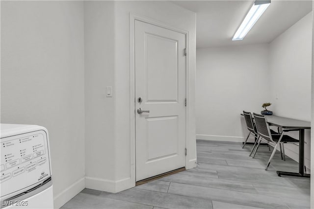 office with washer / clothes dryer, light wood-type flooring, and baseboards