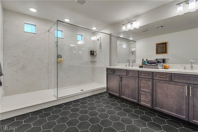 bathroom with a stall shower, visible vents, and a sink