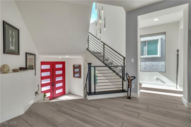 foyer entrance featuring wood finish floors, french doors, stairway, and baseboards