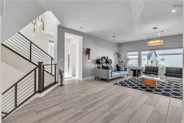 living area with stairs, wood finish floors, visible vents, and baseboards