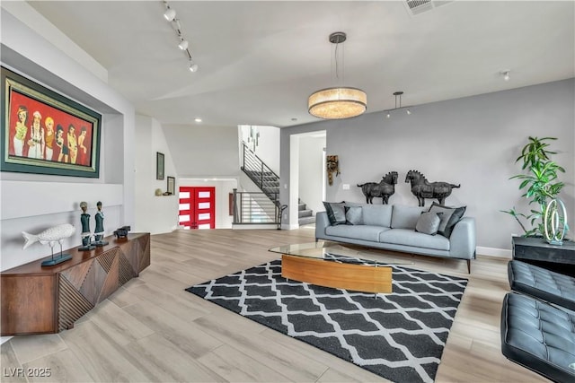 interior space with stairway, wood finished floors, rail lighting, and baseboards