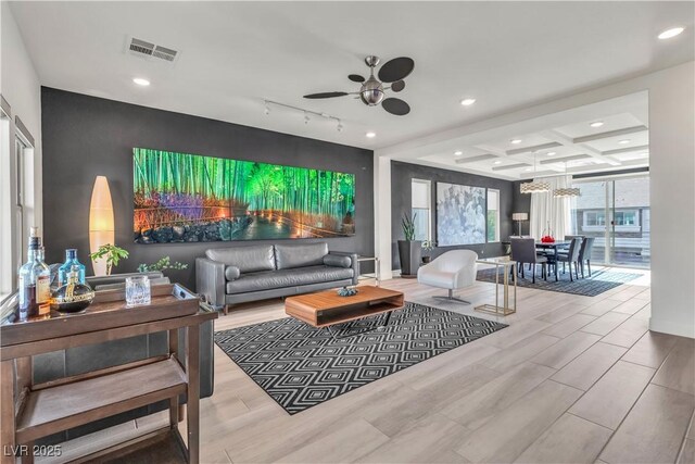 living room with coffered ceiling, rail lighting, light wood-type flooring, ceiling fan, and beam ceiling