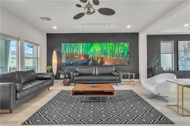 living room with recessed lighting, an accent wall, wood finished floors, visible vents, and baseboards