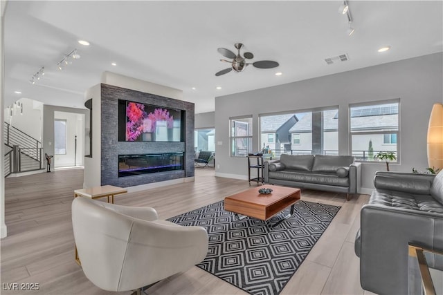 living room with light hardwood / wood-style flooring, a healthy amount of sunlight, and track lighting